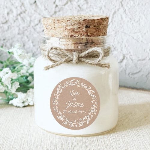 Bougie parfumée personnalisée mariage avec étiquette kraft, couronne florale blanche et ruban rose poudré, idéale comme faveur de mariage ou cadeau de remerciement pour les invités.