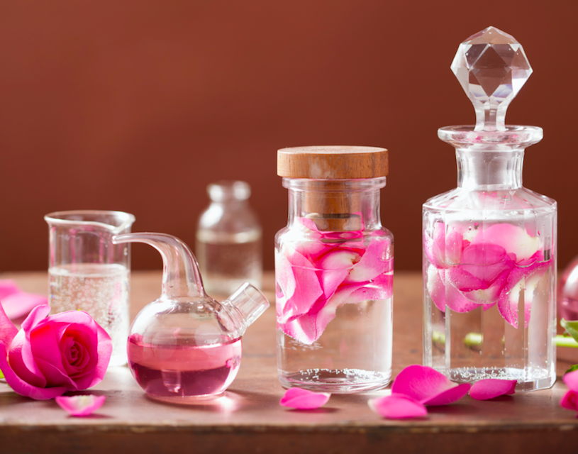 Flacons de parfumerie ancienne et pétales de rose inspirant la bougie parfumée Rose Ancienne